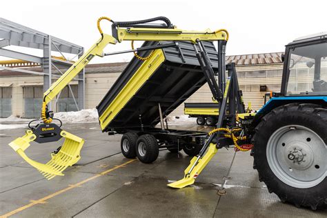 nuotrauka, vaizduojanti traktoriaus priekabą su manipuliatoriumi, atliekančią krovimo darbus