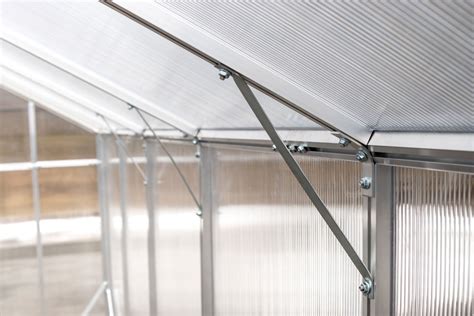 nuotrauka, kurioje matomas polikarbonatinio šiltnamio surinkimo procesas, pavyzdžiui, tvirtinamas polikarbonatas prie karkaso