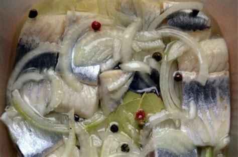 lėkštė su marinuota silkės filė, apibarstyta svogūnų ir džiovintų vaisių mišiniu