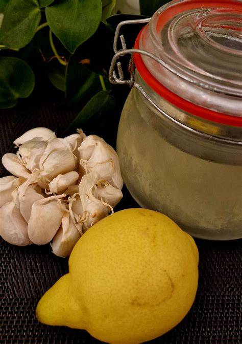 Nuotrauka su paruoštu imbiero, česnako ir citrinos mišiniu stiklainyje, šalia esančiais produktais.