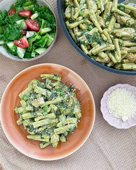 Nuotrauka su paruoštais makaronais su špinatais ir pomidorais, papuoštais baziliku ir sūriu.