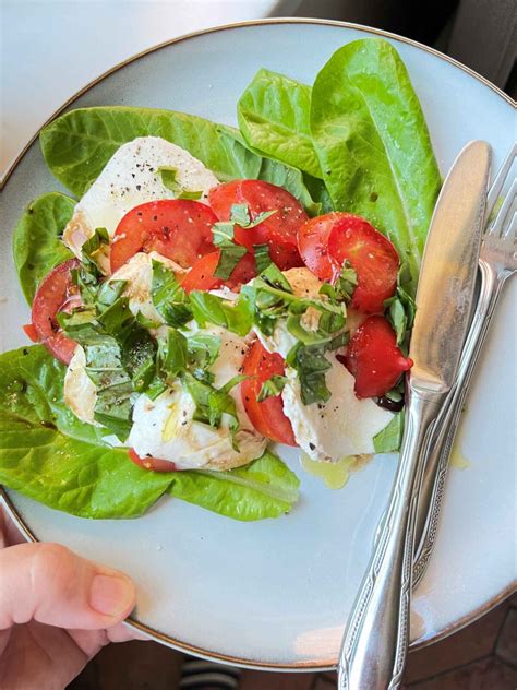 Spalvinga ir estetiška Kaprio salotų lėkštė su mocarela, pomidorais ir baziliku