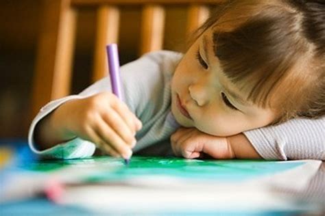 Vaikas piešia ir rašo savo eksperimento dienoraštyje.